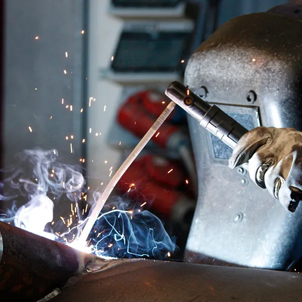 Industrielles Schutzgasschweißen mit Handschuhen und Schutzmaske.