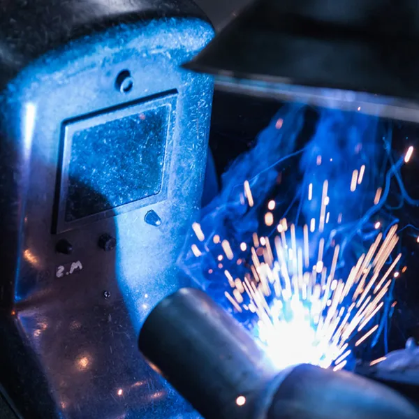 Schweißarbeiten an einer Rohrkonstruktion mit blauem Lichtbogen.