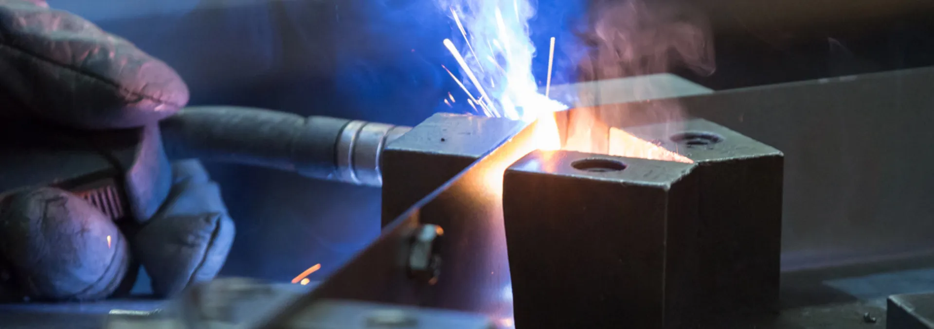 Nahaufnahme eines Schweißvorgangs mit Funkenflug beim Verbinden zweier Metallplatten.